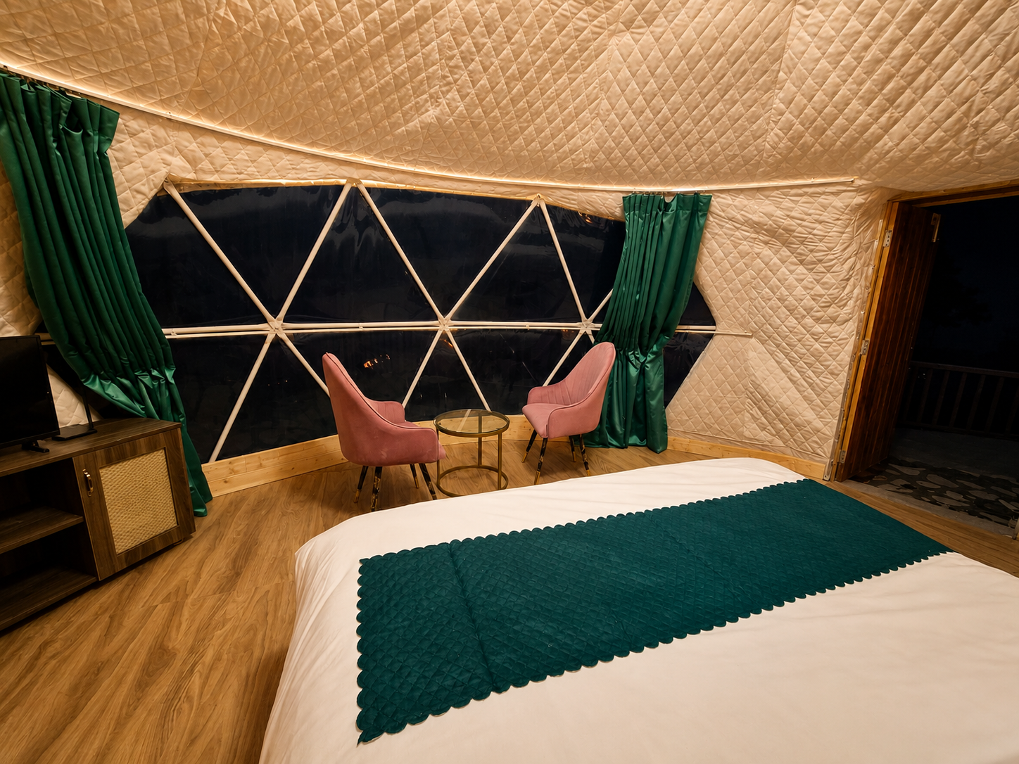 Bed facing the glass dome window with panoramic mountain views